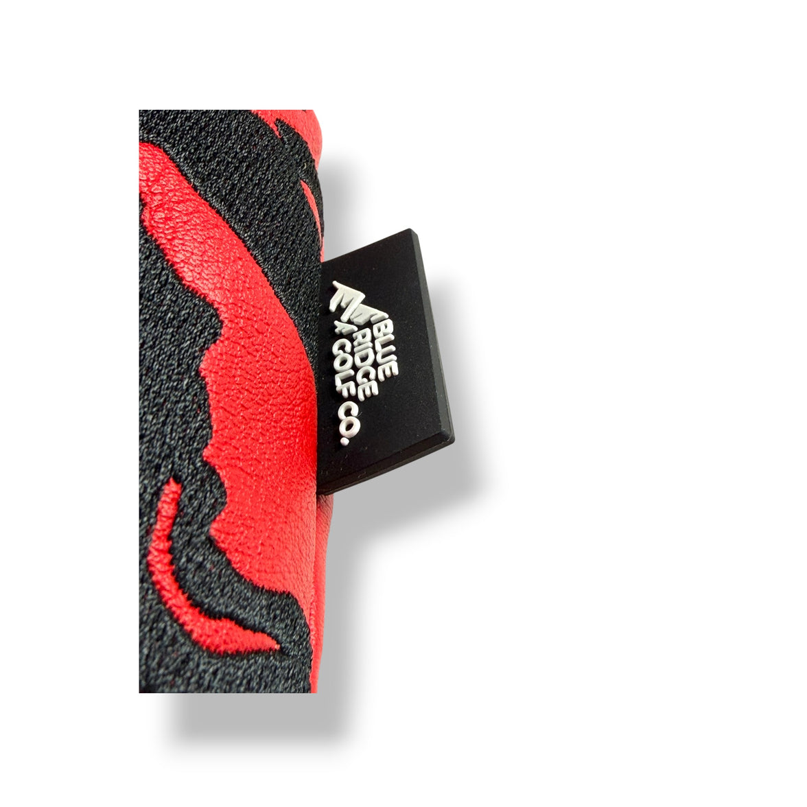 A close-up of a black and red textured tab with a black square label that reads blue ridge golf co in white text, set against a plain white background.