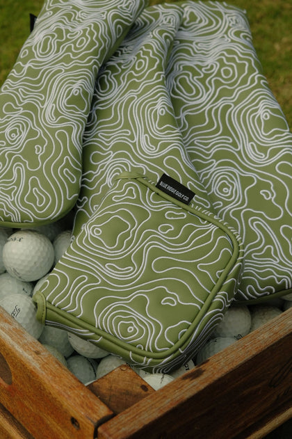Green and white patterned golf bag with a tag on top of golf balls.