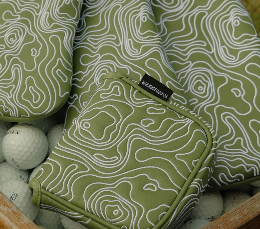 Green and white patterned golf bag with a tag on top of golf balls.