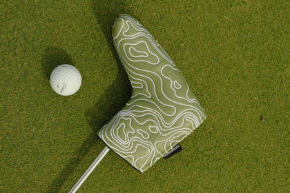 Golf club head cover with topographic design on a green golf course