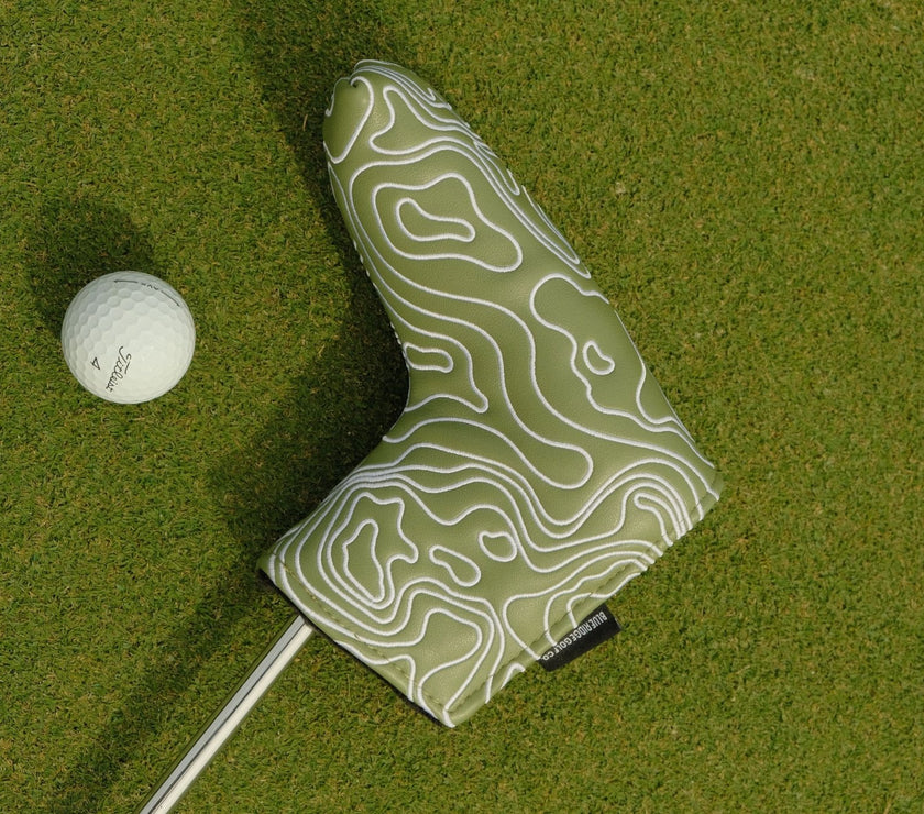 Golf club head cover with topographic design on a green golf course